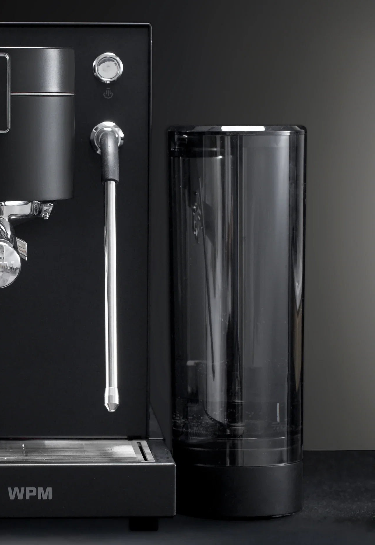 Black WPM PRIMUS espresso machine with a clear container on a dark background